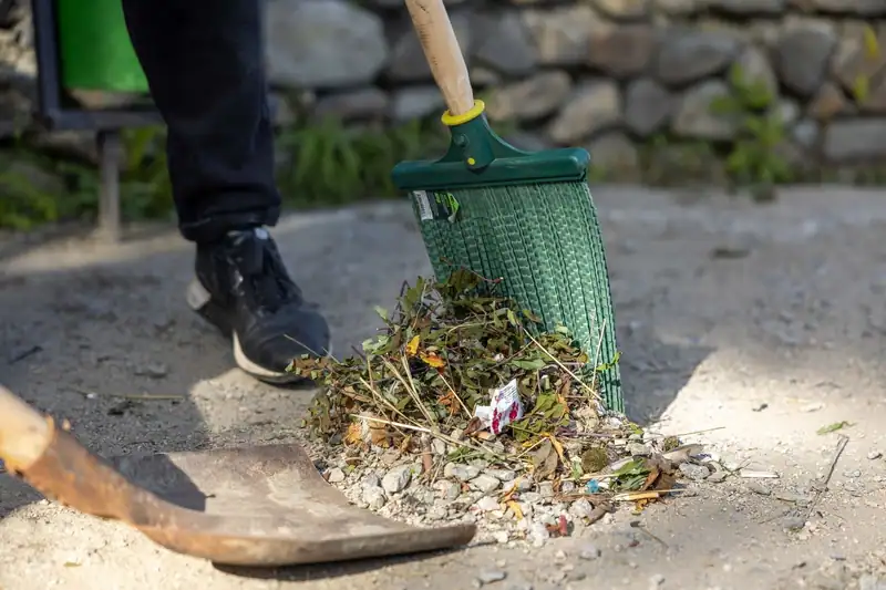 A rake and shovel gathering a pile of yard debris