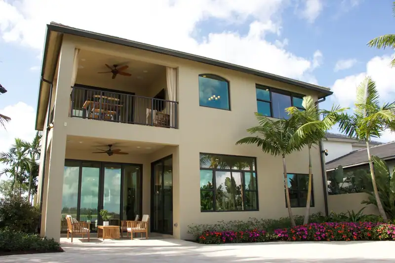 A two-storey stucco home with palms and a kept lawn
